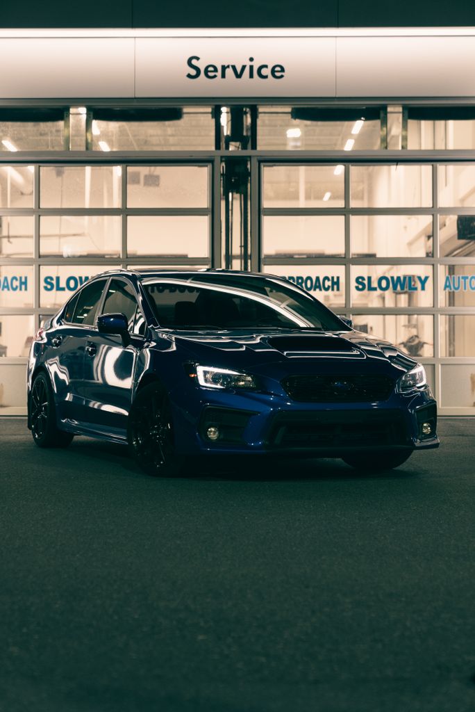 A modern blue car parked in an automotive service area at night, showcasing design and technology.